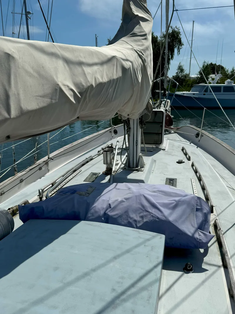 Slide: The Image of 1975 Westsail 32 sailboat deck with covered sails, docked in a marina. - 11