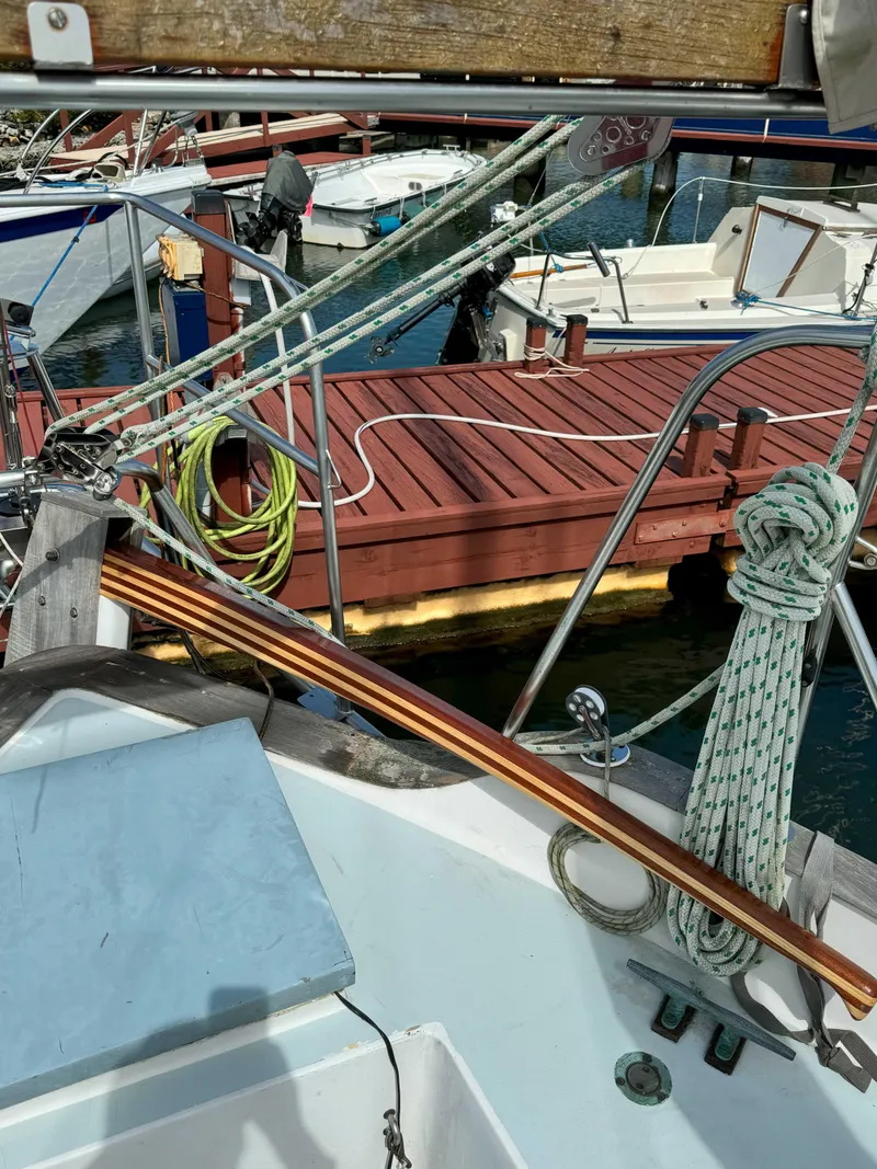 Slide: The Image of 1975 Westsail 32 sailboat docked, featuring ropes and wooden deck in a marina setting. - 12