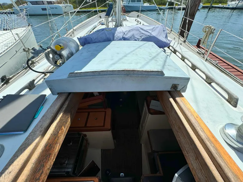 Slide: The Image of 1975 Westsail 32 sailboat deck view with open cabin entrance, docked at marina. - 13