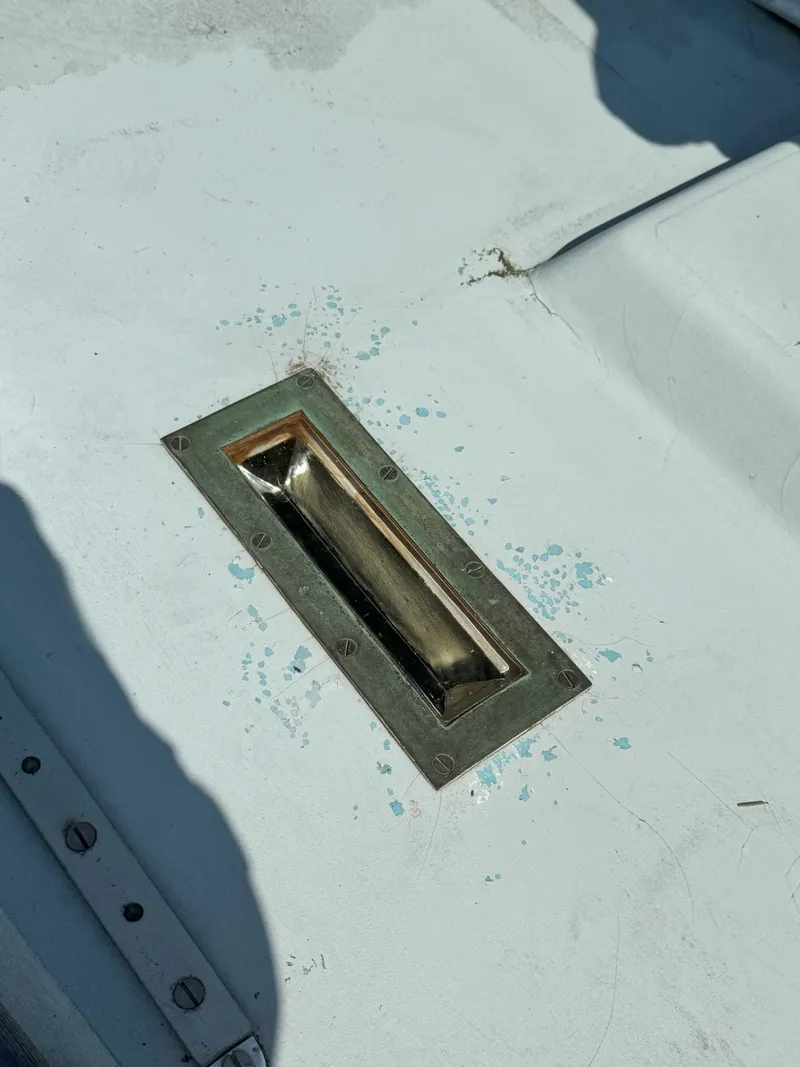 Slide: The Image of 1975 Westsail 32 deck detail with metal fitting and weathered surface. - 15