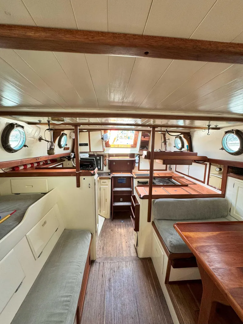 Slide: The Image of Interior of a 1975 Westsail 32 sailboat, featuring cozy seating and wooden accents. - 18
