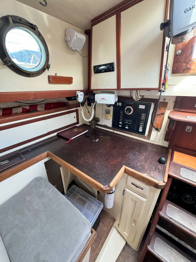 Slide: The Image of 1975 Westsail 32 interior with navigation station, wooden cabinetry, and porthole window. - 19