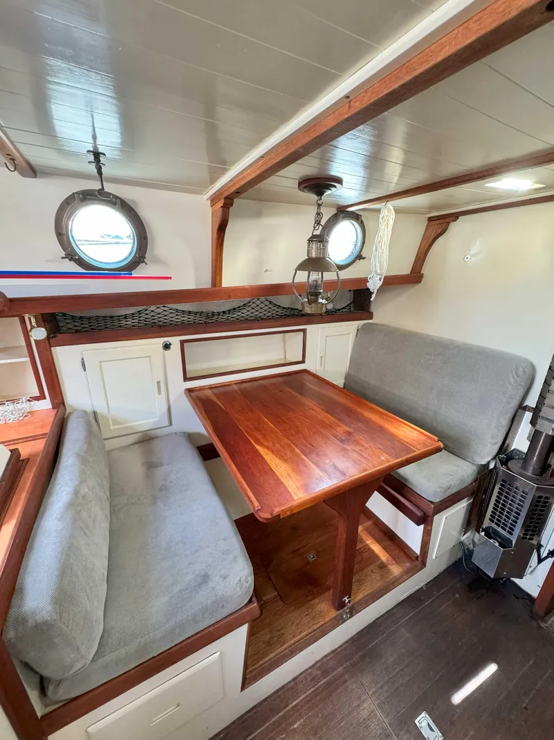 Slide: The Image of Interior of a 1975 Westsail 32 sailboat with wooden table and cushioned seating. - 20