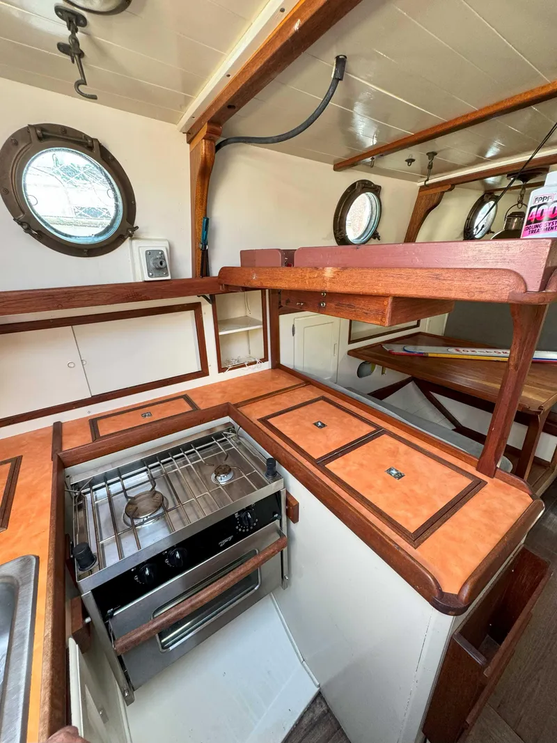 Slide: The Image of 1975 Westsail 32 yacht interior with wooden cabinetry and compact kitchen area. - 22