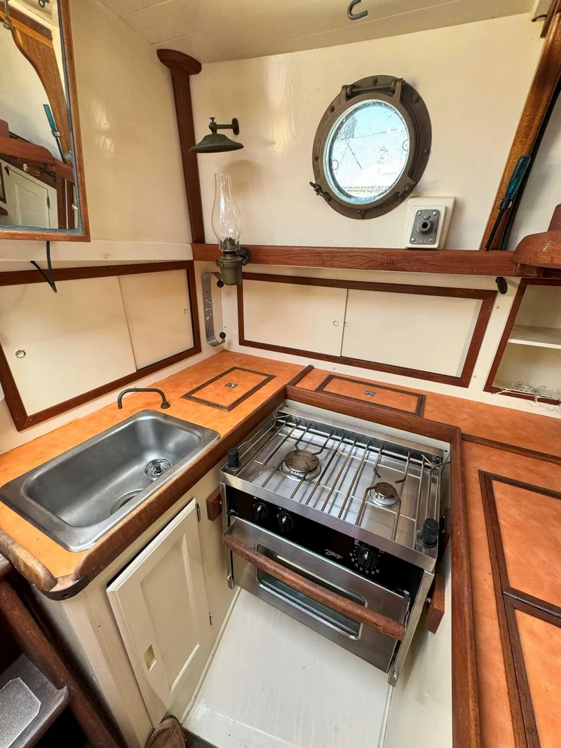 Slide: The Image of 1975 Westsail 32 yacht kitchen with stove, sink, and porthole window. - 23
