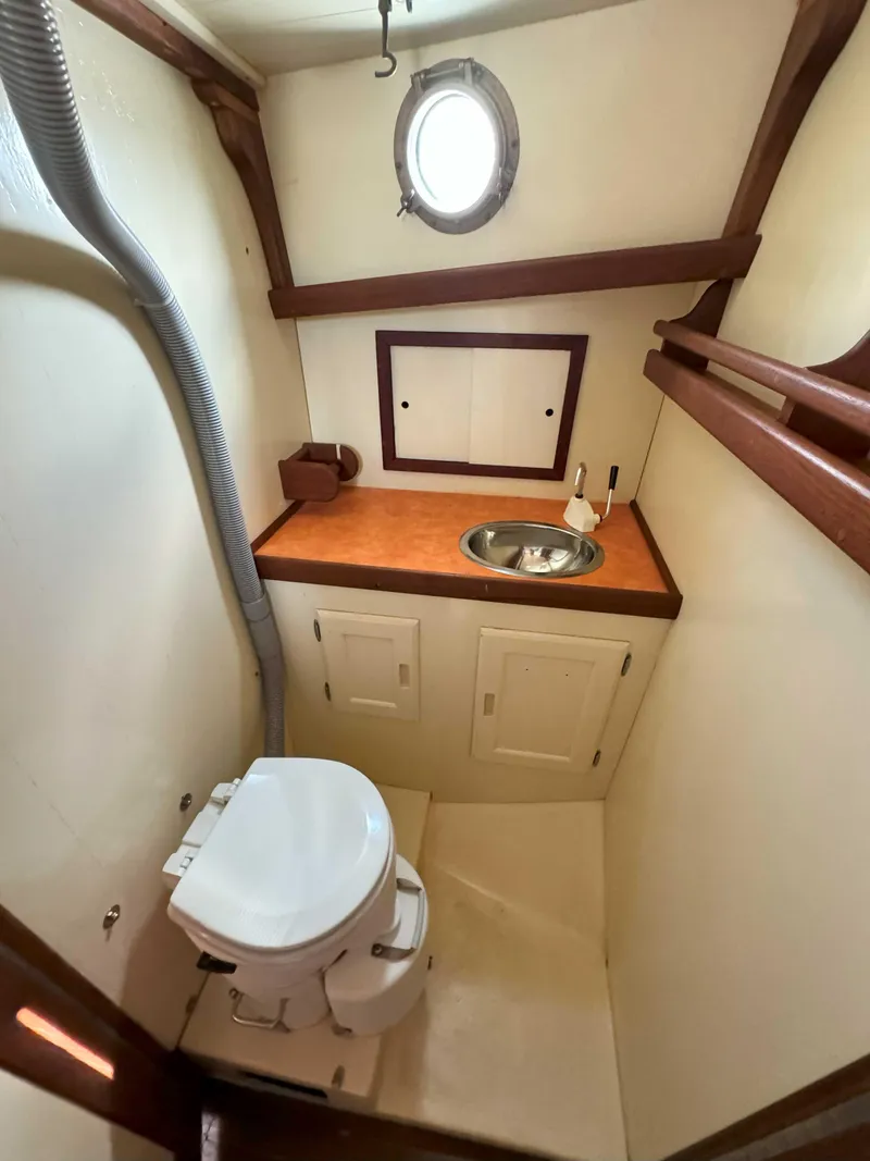 Slide: The Image of 1975 Westsail 32 boat bathroom with porthole, sink, and toilet. - 25