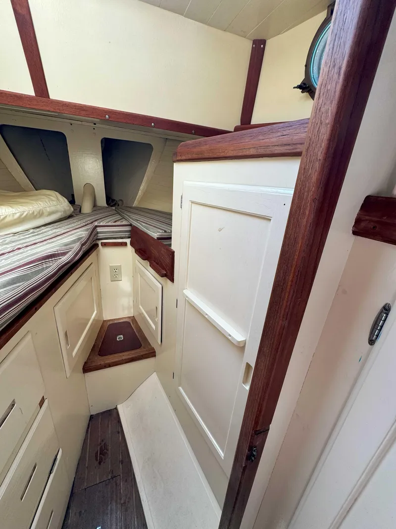 Slide: The Image of 1975 Westsail 32 interior cabin with wood accents and cozy sleeping area. - 26