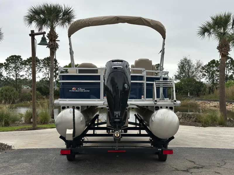 Slide: The Image of 2025 Sun Tracker Fishin' Barge 20 DLX pontoon boat on trailer, parked outdoors. - 3