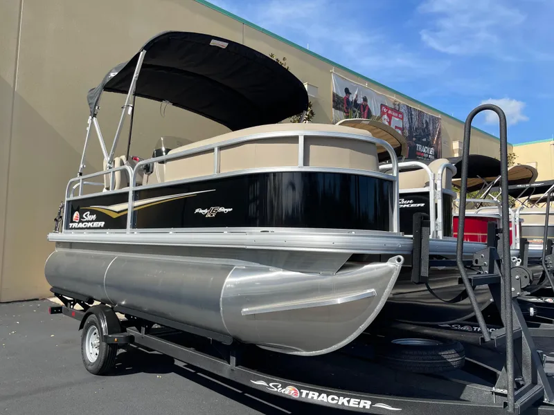 Slide: The Image of 2025 Sun Tracker Party Barge 16 DLX pontoon boat on trailer, outdoor display. - 2