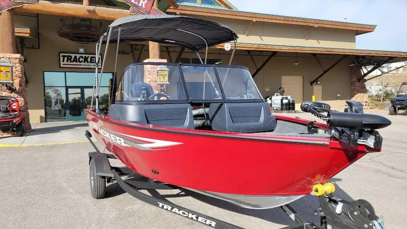 Slide: The Image of 2025 Tracker Pro Guide V-16 WT boat, red, parked outside dealership. - 2