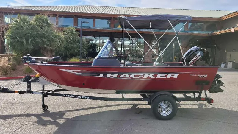 Slide: The Image of 2025 Tracker Pro Guide V-16 WT boat on trailer, red exterior, parked outdoors. - 3