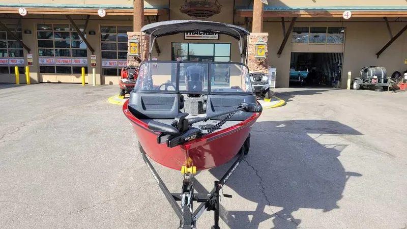 Slide: The Image of 2025 Tracker Pro Guide V-16 WT boat in front of a store, red exterior. - 5