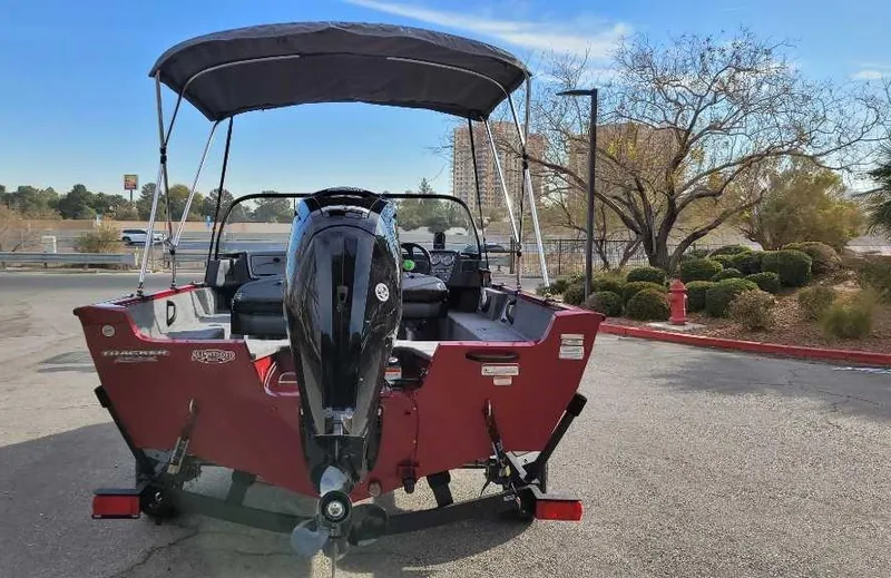 Slide: The Image of 2025 Tracker Pro Guide V-16 WT boat with canopy, parked outdoors. - 7