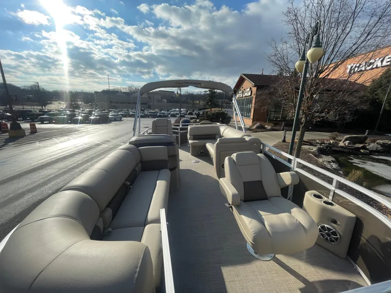Slide: The Image of 2025 Sun Tracker SportFish 20 DLX pontoon boat with spacious seating and canopy under a sunny sky. - 2