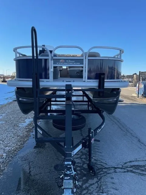 Slide: The Image of 2025 Sun Tracker Bass Buggy 18 DLX pontoon boat on trailer, front view. - 2