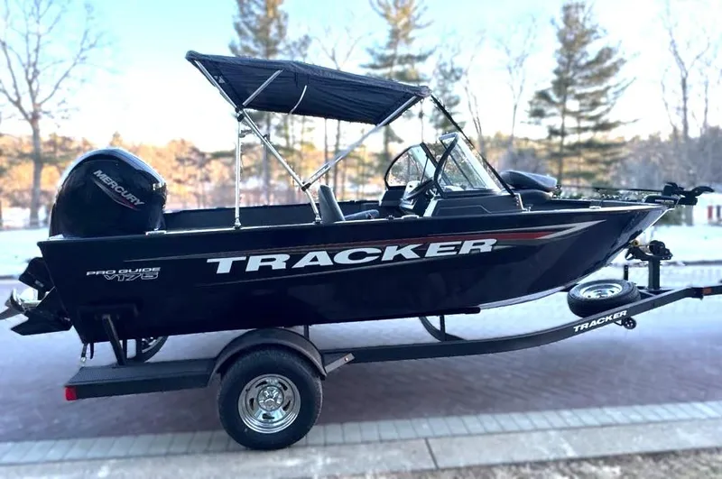 Slide: The Image of 2025 Tracker Pro Guide V-175 Combo boat on trailer, black exterior, parked outdoors. - 2