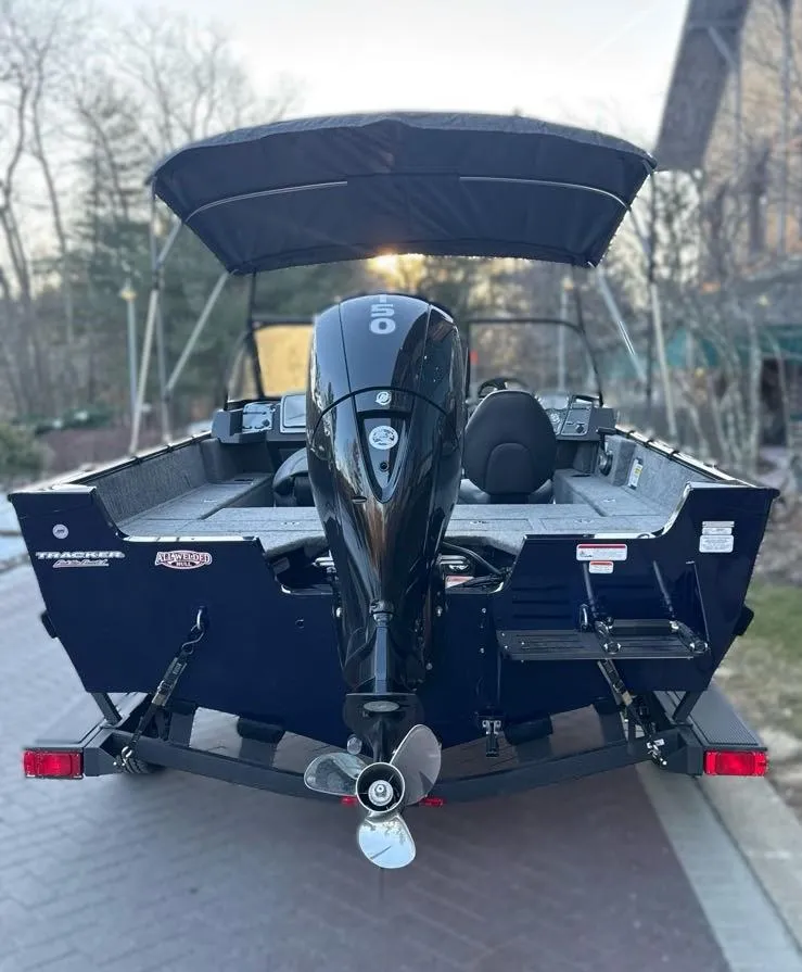 Slide: The Image of 2025 Tracker Pro Guide V-175 Combo boat with outboard motor, parked on a driveway. - 5