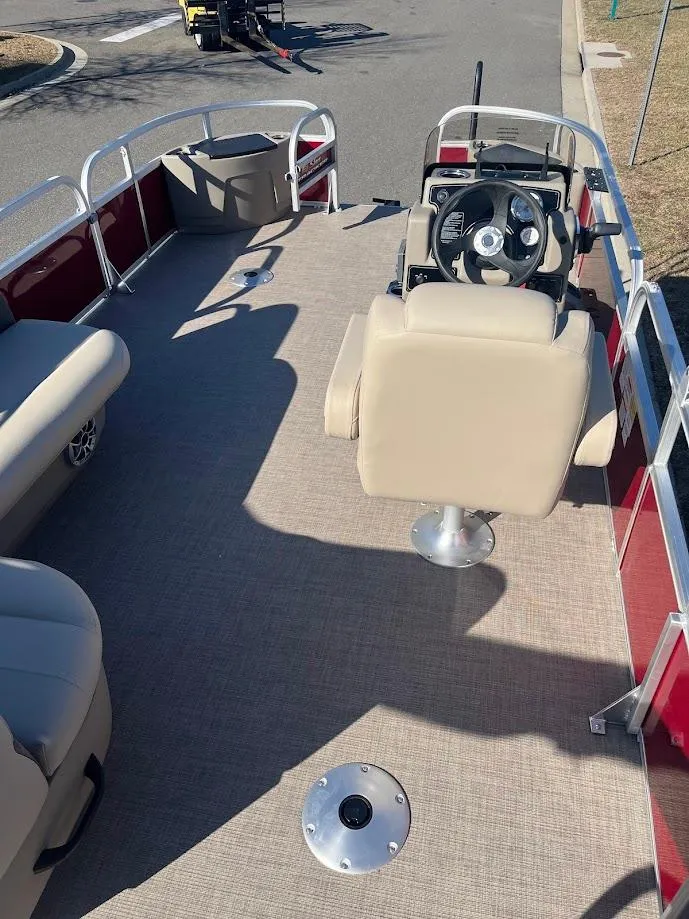 Slide: The Image of 2025 Sun Tracker Bass Buggy 18 DLX pontoon boat interior with beige seating and steering console. - 3