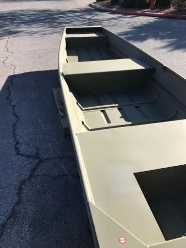 Slide: The Image of 2025 Tracker Grizzly 1436 Utility boat on pavement, showcasing interior seating and storage. - 3