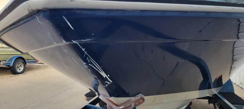 Slide: The Image of 1986 Four Winns 160 Freedom boat with visible hull scratches on a trailer. - 16