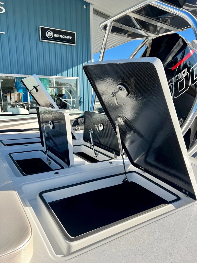 Slide: The Image of 2025 Chittum Skiffs 21R boat with open storage compartments and Mercury engine in a showroom. - 4