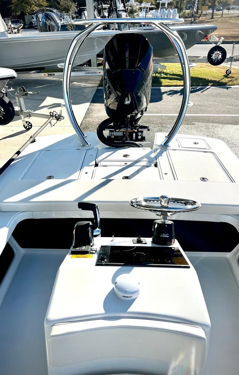 Slide: The Image of 2025 Chittum Skiffs 21R boat interior with steering wheel and controls, docked outdoors. - 6