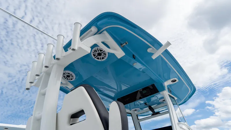 Slide: The Image of 2025 Tidewater 320 CC Adventure boat with blue canopy and rod holders under a cloudy sky. - 23
