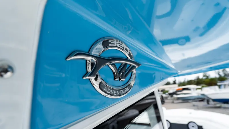 Slide: The Image of 2025 Tidewater 320 CC Adventure boat emblem on blue hull. - 24