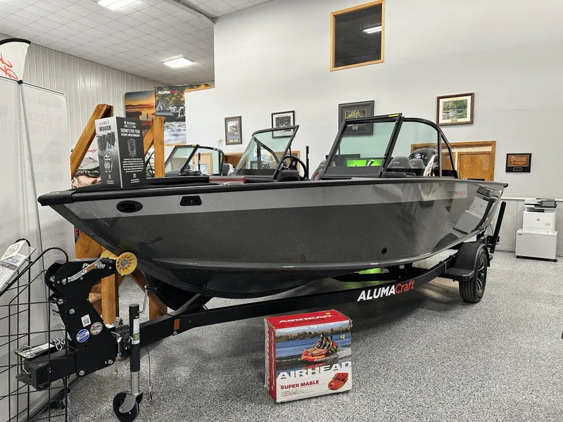 The Image of 2025 Alumacraft Trophy 185X Sport boat on trailer outside marine store. - 0