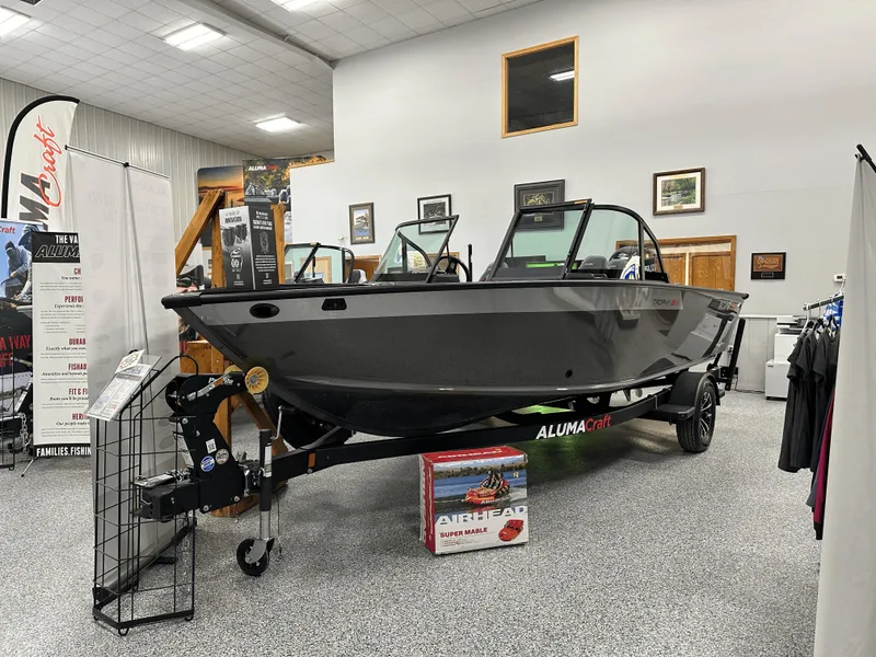 Slide: The Image of 2025 Alumacraft Trophy 185X Sport boat with motor, displayed outdoors on gravel. - 18