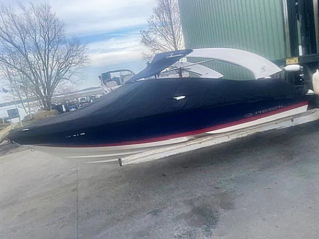 Slide: The Image of 2021 Regal 2000 ES Bowrider boat covered, parked outdoors near a green building. - 4