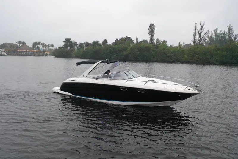 Slide: The Image of 2005 Regal 3350 Sport Cruiser on a calm lake with lush greenery. - 6