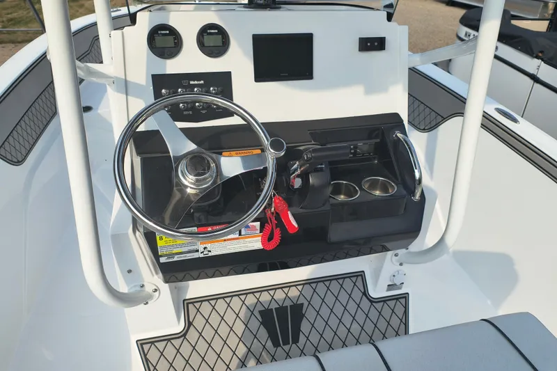 Slide: The Image of 2025 Wellcraft 202 Fisherman boat dashboard with steering wheel and controls. - 14