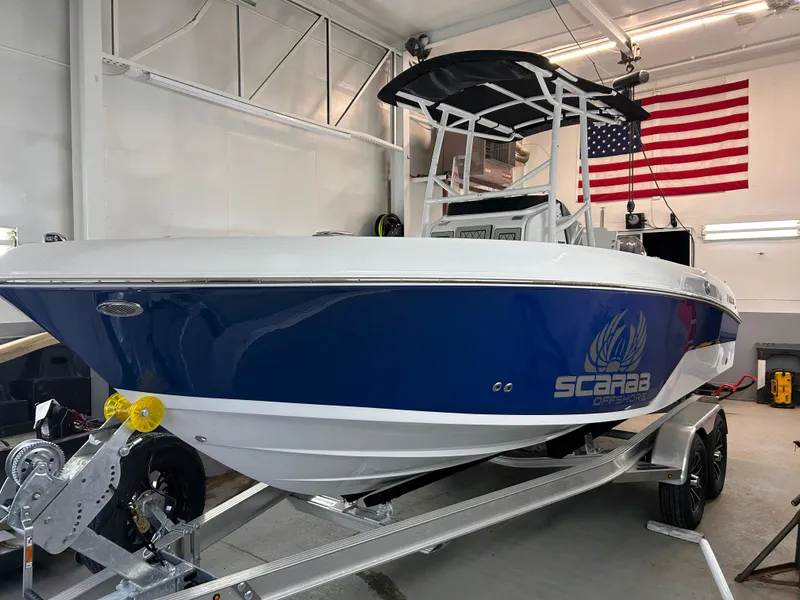 Slide: The Image of 2025 Wellcraft 202 Fisherman boat in garage, blue hull, American flag in background. - 3