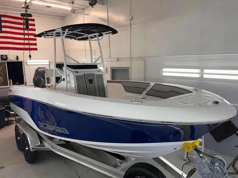 Slide: The Image of 2025 Wellcraft 202 Fisherman boat in a garage, featuring a sleek blue and white design. - 4