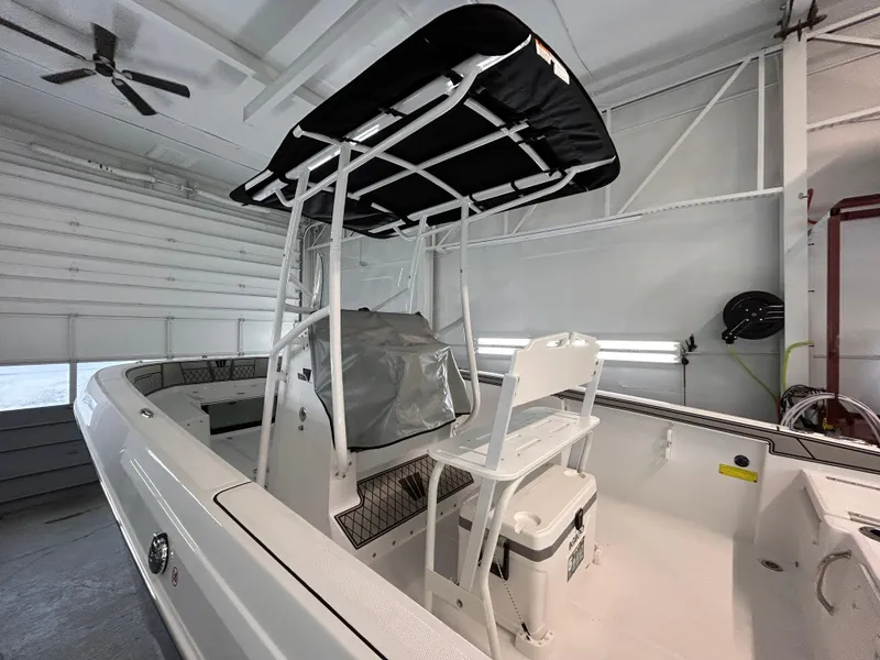 Slide: The Image of 2025 Wellcraft 202 Fisherman boat in a garage, featuring a T-top and seating area. - 8