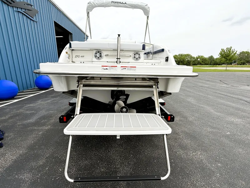 Slide: The Image of 2025 Formula 270 Bowrider boat, rear view with swim platform and ladder, parked outdoors. - 8
