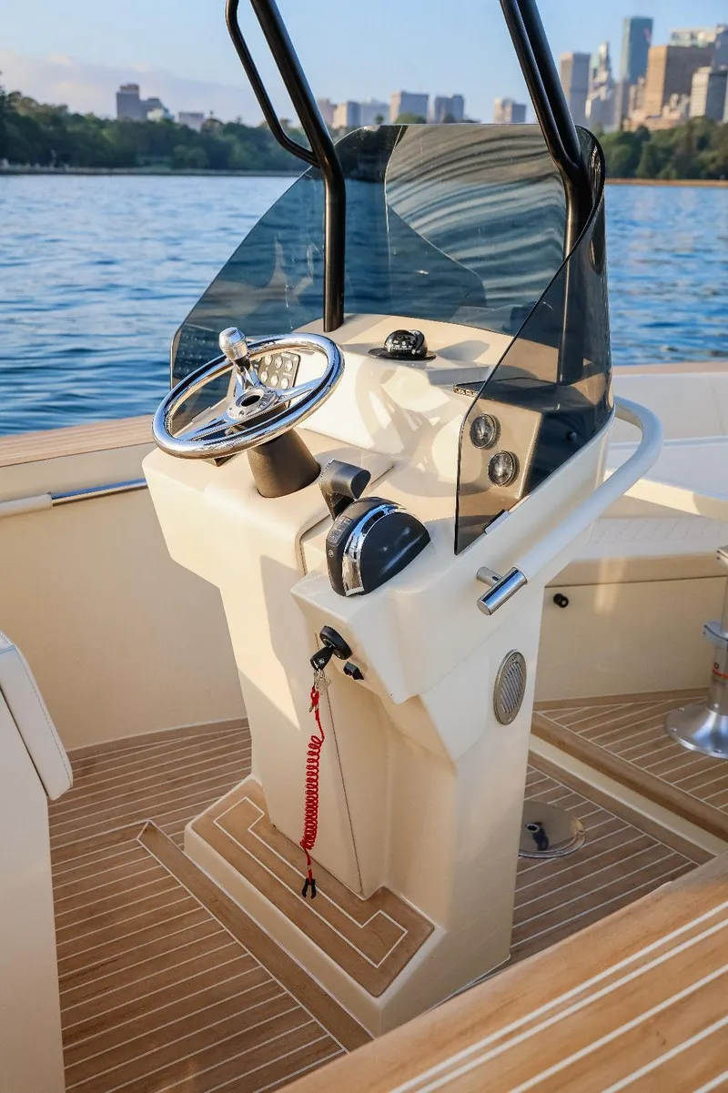 Slide: The Image of 2025 AlCustom Levanzo 25 boat helm with steering wheel and controls, on calm water. - 14