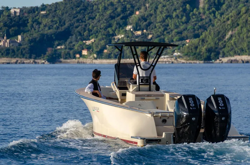 Slide: The Image of 2025 AlCustom Levanzo 25 boat cruising on a scenic lake with two passengers. - 5
