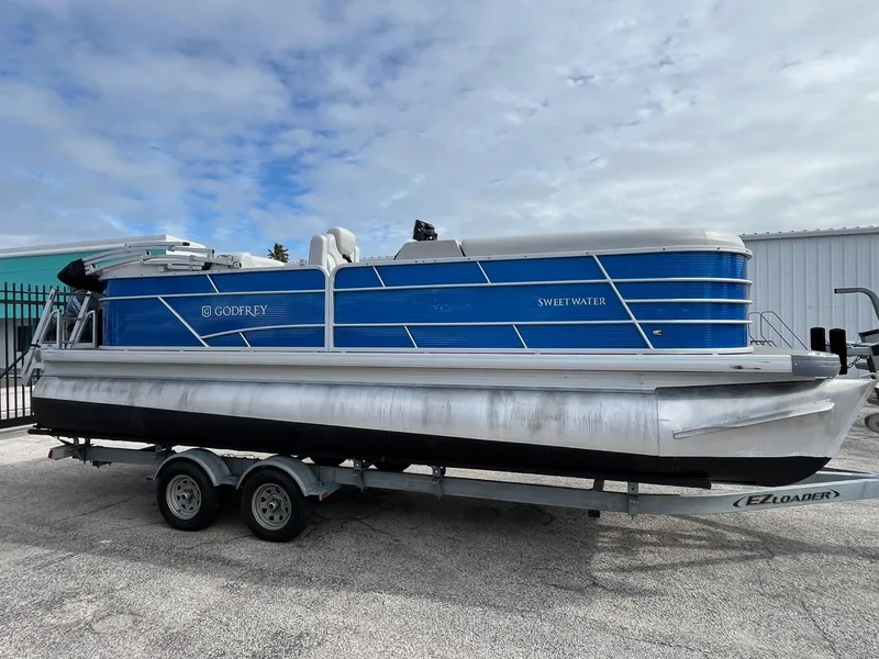 The Image of 2022 Godfrey Sweetwater 2286 C pontoon boat on trailer, blue and silver design. - 0