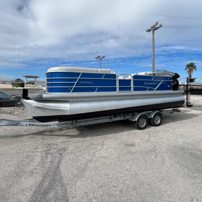Slide: The Image of 2022 Godfrey Sweetwater 2286 C pontoon boat on trailer, blue and silver design at Boateka. - 1