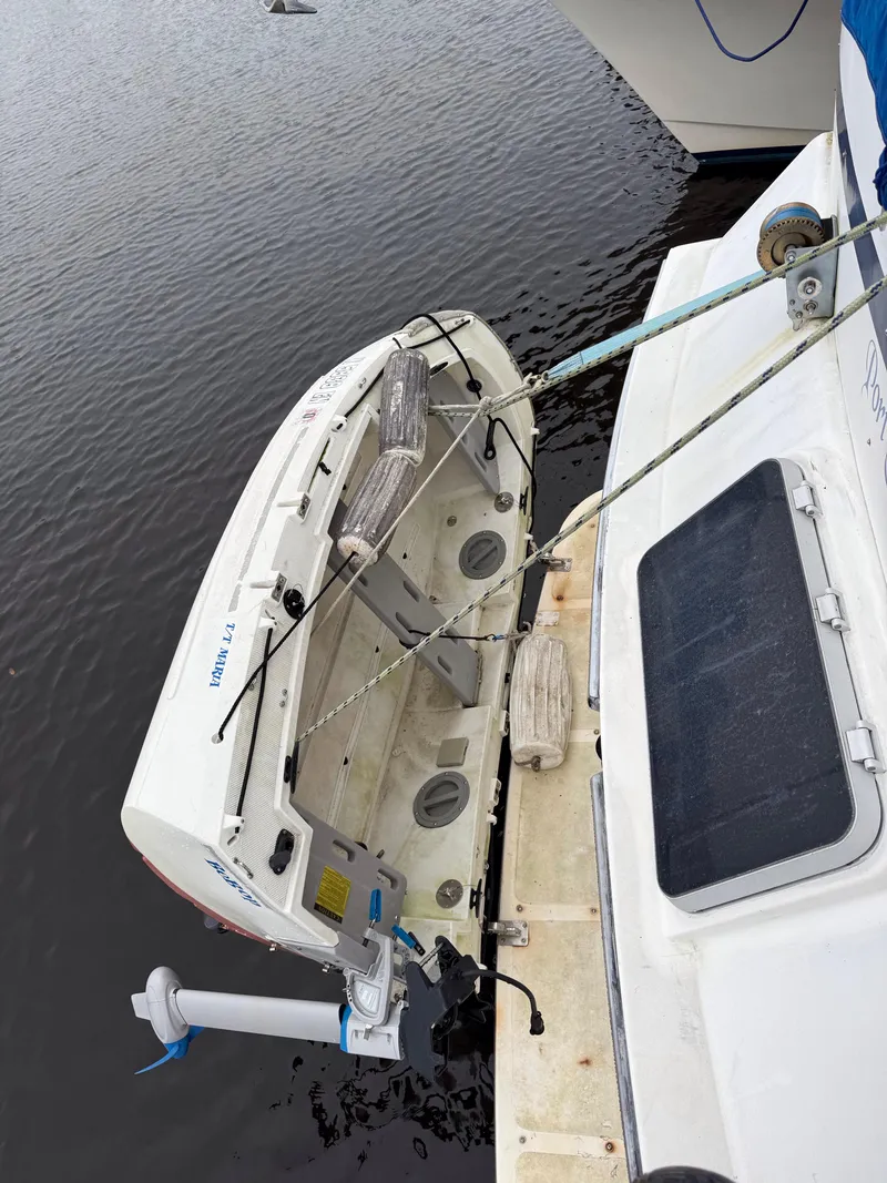Slide: The Image of 1986 Jefferson Sundeck boat with attached dinghy on calm water. - 12