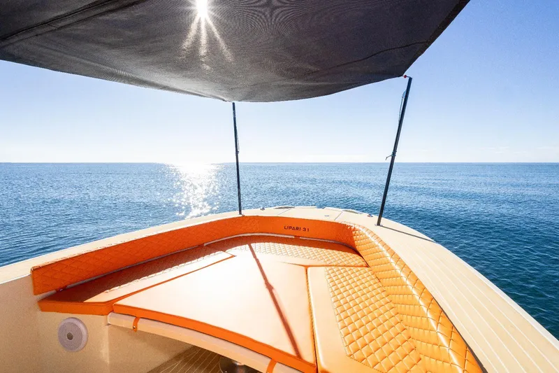 Slide: The Image of AlCustom LIPARI 31 boat, 2025 model, with orange seating, sunshade, and ocean view. - 10