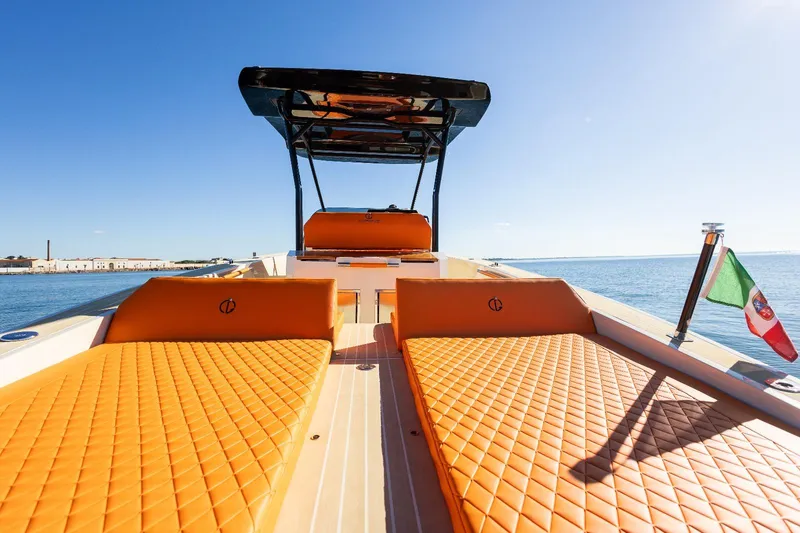 Slide: The Image of 2025 AlCustom LIPARI 31 boat with orange seating, Italian flag, and clear blue sky. - 17