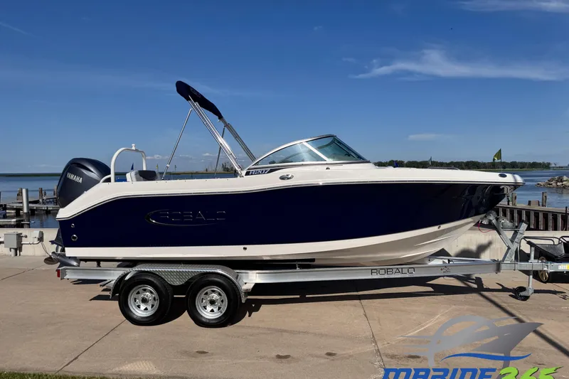 The Image of 2025 Robalo R207 Dual Console boat on trailer by waterfront. - 0