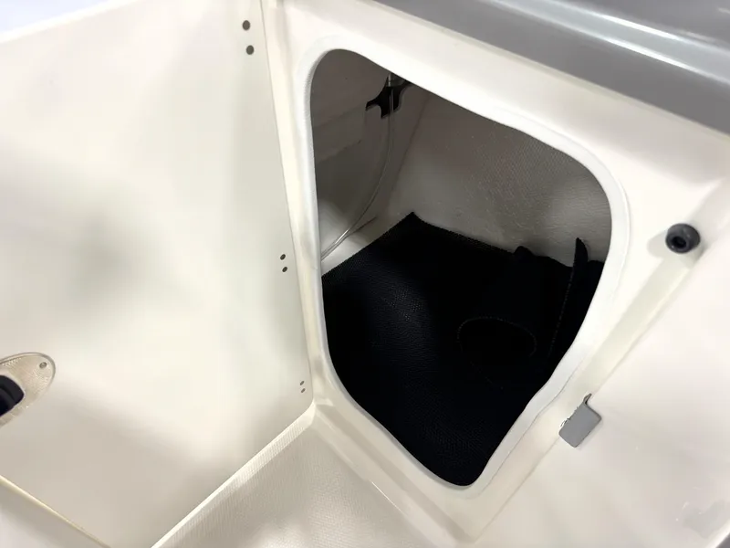 Slide: The Image of 2025 Robalo R207 Dual Console storage compartment, white interior with black mat. - 13