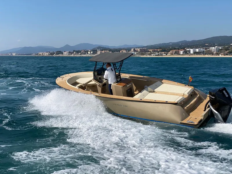 Slide: The Image of AlCustom Levanzo 25 boat cruising on the ocean, 2025 model, with scenic coastal backdrop. - 2