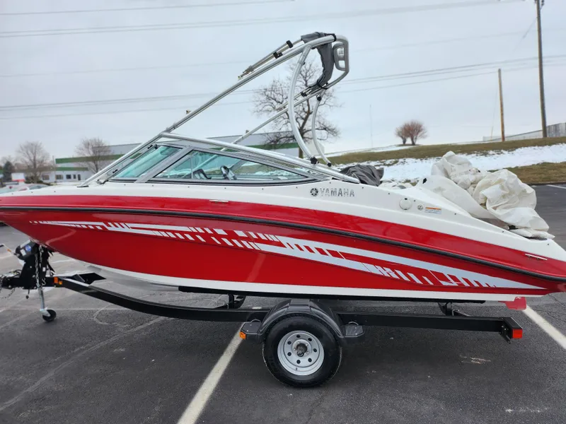 Slide: The Image of 2014 Yamaha AR190 boat in red and white on a trailer, parked outdoors. - 4