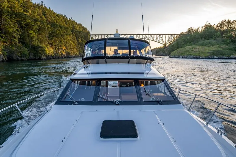 Slide: The Image of 1990 Ocean Alexander 48 Cockpit Motoryacht cruising under a bridge at sunset. - 22