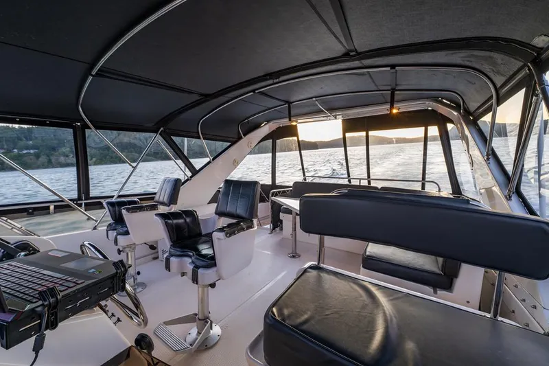 Slide: The Image of 1990 Ocean Alexander 48 Cockpit Motoryacht interior with seating, overlooking serene waters at sunset. - 31